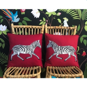 two cushions on chairs showing running zebras background colour is viva magenta