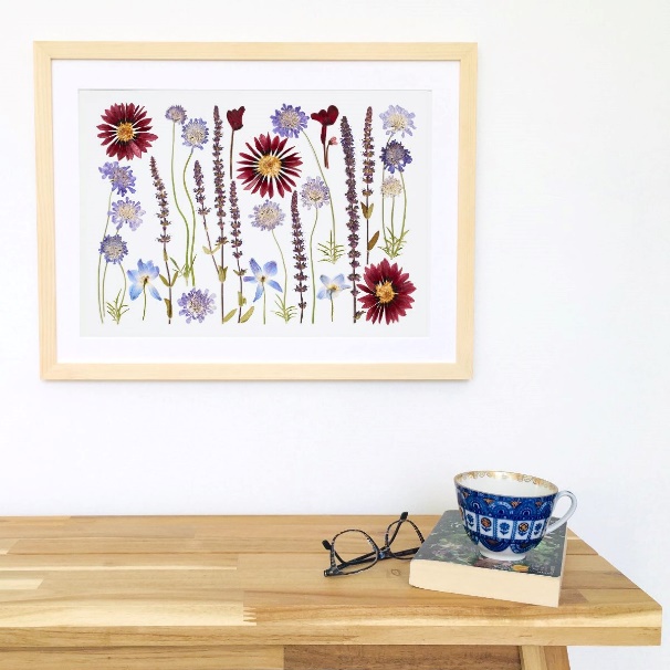 A framed picture of flowers and a cup of coffee on a table

Description automatically generated