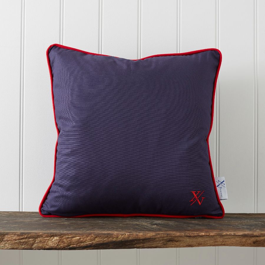 A purple pillow with red trim on a wooden surface Description automatically generated